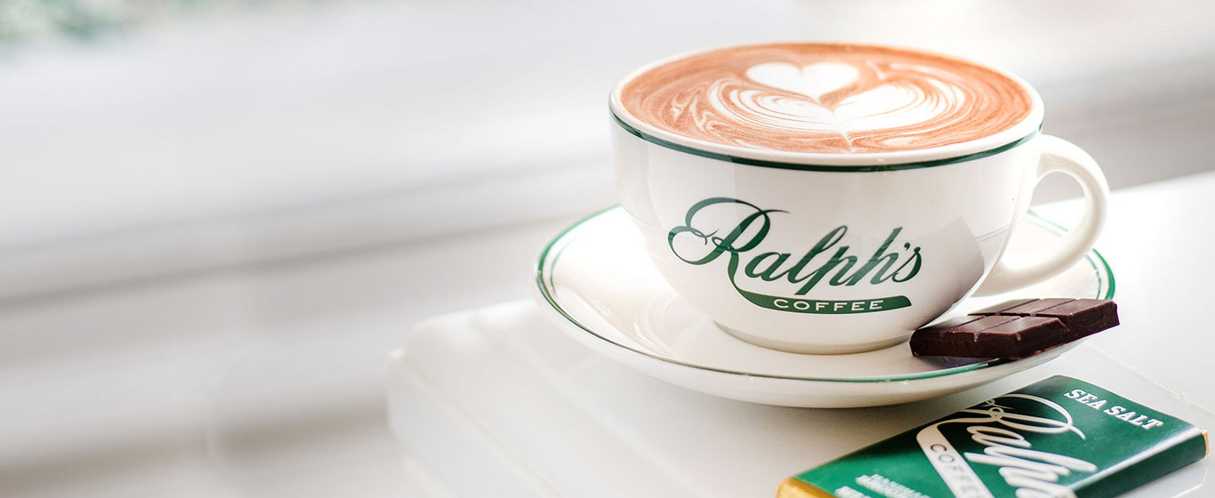 Ralph's Coffee mug with latte art, and bar of Ralph's chocolate.